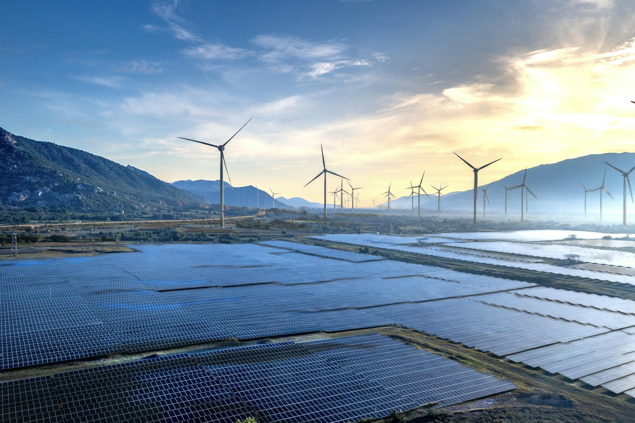 Stunning landscape featuring solar panels and wind turbines at sunrise, symbolizing sustainable energy.
